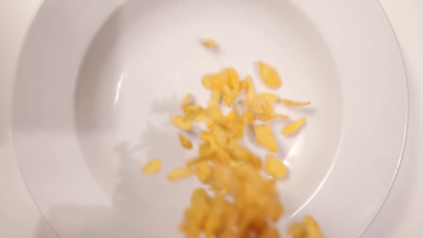 Los copos de maíz caen en una placa en cámara lenta - vista de arriba hacia abajo — Vídeo de stock