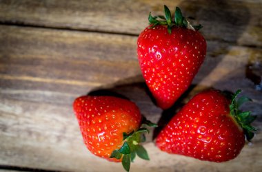 Çilekler yakın planda, ahşap bir masada.