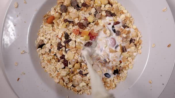 Menuang susu ke atas sereal dan buah kering untuk sarapan — Stok Video