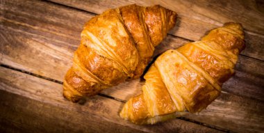 Ahşap bir masada taze pişmiş Fransız kruvasanı.