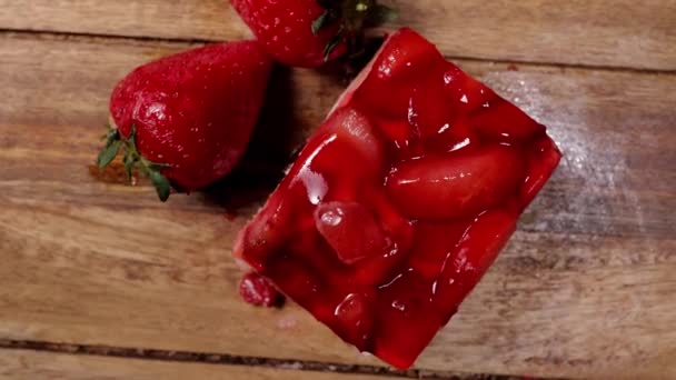 Un delicioso pedazo de pastel de fresa en una mesa de madera — Vídeo de stock