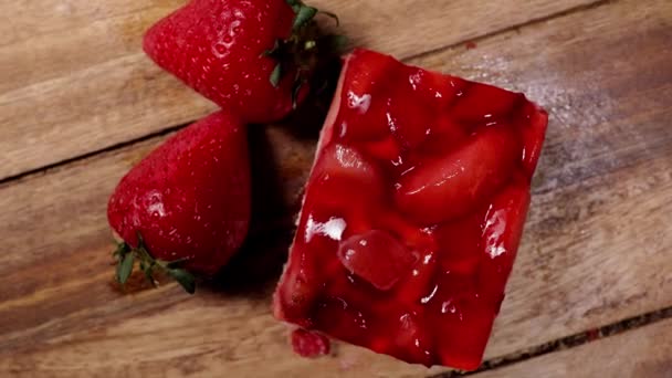 Un delicioso pedazo de pastel de fresa en una mesa de madera — Vídeo de stock