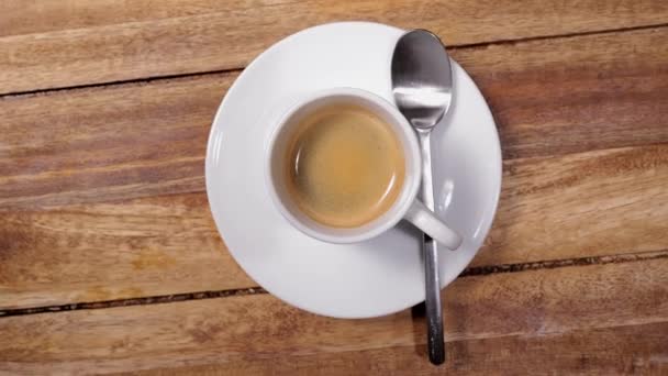 A cup of coffee or espresso on a wooden table - top down view — Stock Video