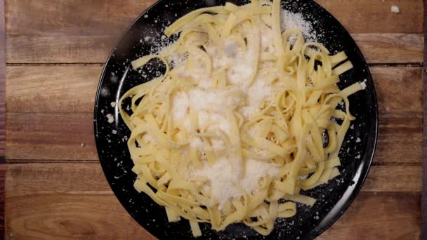 Розбризкуйте пармезанський сир над тарілкою макаронних виробів повільний рух — стокове відео