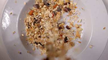 Kahvaltıda mısır gevreğinin üzerine süt ve kurutulmuş meyve dökmek.