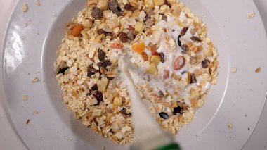 Kahvaltıda mısır gevreğinin üzerine süt ve kurutulmuş meyve dökmek.