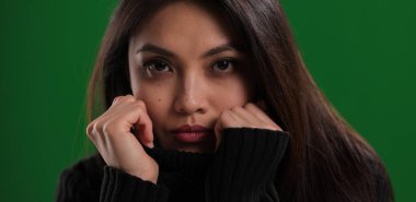 Güzel yüzlü genç bir kadın kameraya bakıyor.