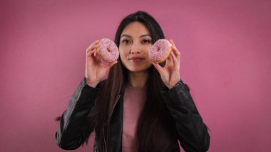 Genç mutlu kadın elinde donut tutuyor.