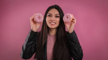 Genç mutlu kadın elinde donut tutuyor.