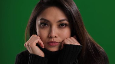 Güzel yüzlü genç bir kadın kameraya bakıyor.