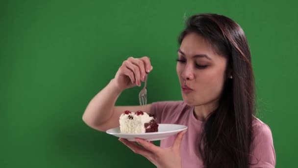 Young woman eats a piece of cream cake with cherries