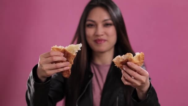 Young woman eats a freshly baked French croissant — Stock Video