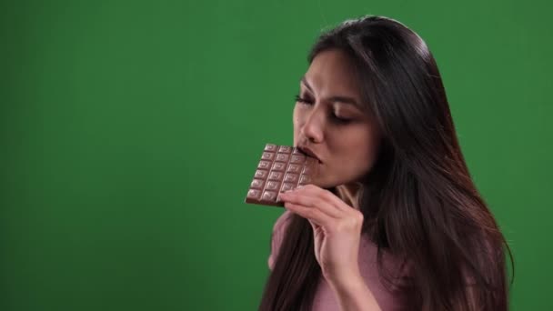 Young woman bites into a bar of chocolate — Stock Video
