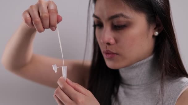 Молодая женщина проводит самоанализ антигена Covid-19 — стоковое видео