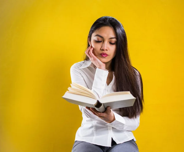 Kitap okuyan genç bir kadın - sarı arka planda stüdyo çekimi — Stok fotoğraf