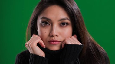 Güzel yüzlü genç bir kadın kameraya bakıyor.