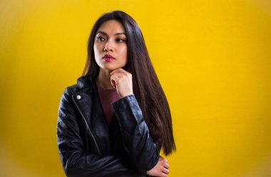 Sarı arka planda kendine güvenen genç bir kadının portresi.