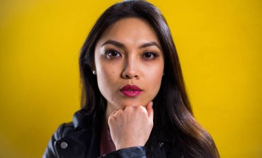 Sarı arka planda kendine güvenen genç bir kadının portresi.