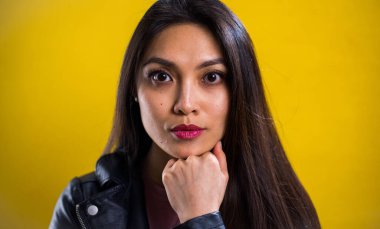 Sarı arka planda kendine güvenen genç bir kadının portresi.