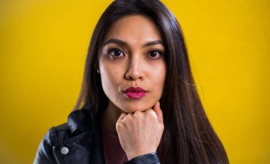 Sarı arka planda kendine güvenen genç bir kadının portresi.