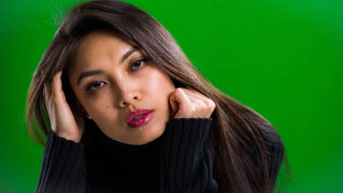 Stüdyoda kameraya poz veren genç ve güzel bir kadın.