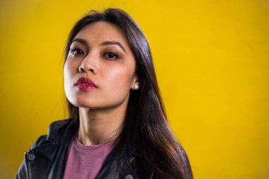 Sarı arka planda kendine güvenen genç bir kadının portresi.