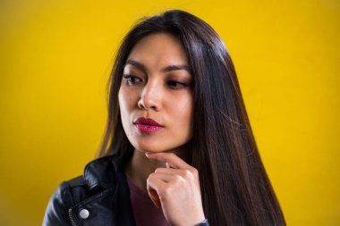 Sarı arka planda kendine güvenen genç bir kadının portresi.