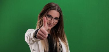 Genç ve güzel bir kadın baş parmak hareketi yapıyor.