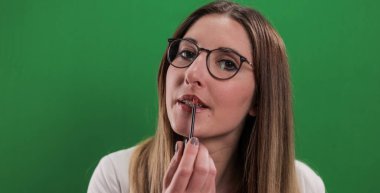 Genç ve güzel kadın dudaklarını yapıyor.