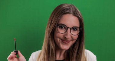 Genç ve güzel bir kadın dudak nemlendiricisi sürüyor.