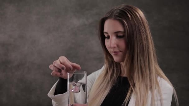 Mujer joven arroja una tableta de vitaminas en un vaso de agua — Vídeos de Stock