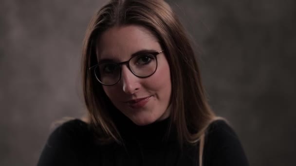 Close-up of a young attractive woman against dark grey background — Stock Video