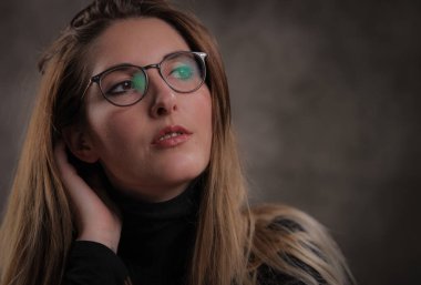 Koyu gri arka planda genç ve çekici bir kadının yakın çekimi.