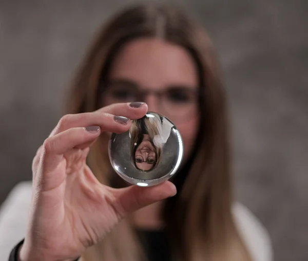 Mooie vrouw kijkt door een glazen bal — Stockfoto