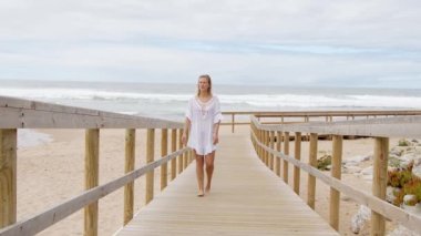 Güzel bir kadın ahşap bir iskelede yürüyor - aşırı yavaş çekim