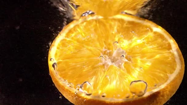 オレンジの新鮮なスライスが水に落ちる スローモーションマクロショット — ストック動画