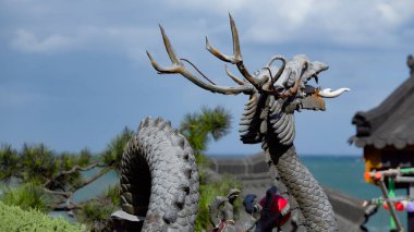 BUSAN, Güney Kore - 9 Ekim 2025 Güney Kore 'deki okyanusa bakan Budist tapınağında boynuzlu ejderha heykeli