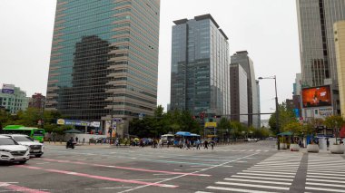 SEOUL, Güney Kore - 11 Ekim 2025 - İnsanlar Seul 'deki modern binalarla çevrili bir kavşakta karşıdan karşıya geçiyorlar