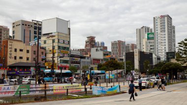 BUSAN, Güney Kore - 9 Ekim 2025 - Busan, Güney Kore 'de binalar, araçlar ve yayalar bulutlu bir gökyüzü altında