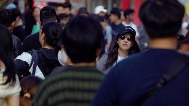 BUSAN, Güney Kore - 9 EKİM 2025 Busan, Güney Kore 'de kalabalık bir caddede genç bir kadın