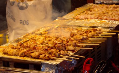 Barbekü tezgahında ızgara yapan tavuk şişleri. Lezzetli Kore sokak yemekleri hazırlıyorlar.