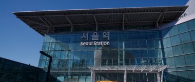 Çağdaş bir bina olan Seul İstasyonu, mavi gökyüzüne karşı geniş bir cam cephe içerir.