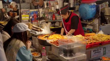 SEOUL, GÜNEY KOREA - 11 EKİM 2025 - Krupiye, müşteri için tteokbokki ve odeng gibi popüler Kore sokak yemekleri hazırlıyor