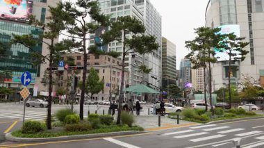 SEOUL, Güney Kore - 11 Ekim 2025 - Güney Kore 'de binalar, trafik, yayalar ve çam ağaçları ile şehir caddesi