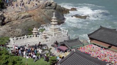 BUSAN, Güney Kore - 10 EKİM 2025 - Haedong Yonggungsa Tapınağı, güneşli bir günde birçok ziyaretçiyle kıyı şeridinde