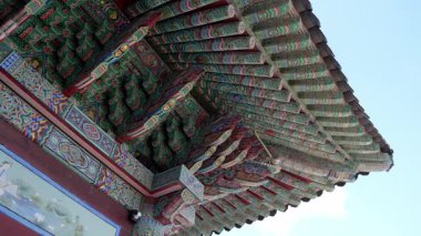 BUSAN, Güney Kore - 10 EKİM 2025 - Dancheong 'un mavi gökyüzüne karşı rengarenk resim desenlerini gösteren tapınak çatısı