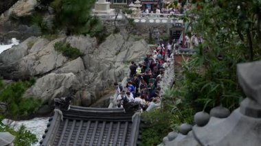 BUSAN, Güney Kore - 10 Ekim 2025 Haedong Yonggungsa Tapınağı kıyı şeridi boyunca köprü ve kayaları keşfeden turistler