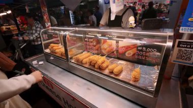 SEOUL, Güney Kore - 11 Ekim 2025 - Myeongdong sokak yiyecek satıcısı Koreli mısırlı sosis ve patates sosisi satıyor
