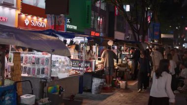 SEOUL, Güney Kore - 11 Ekim 2025 Myeongdong, Seul 'deki kalabalık bir gece pazarında sokak yemekleri ve alışveriş yapan insanlar