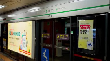 SEOUL, Güney Kore - 11 Ekim 2025 - İstasyona gelen tren peron kapılarını reklamlarla ve CCTV tabelasıyla gösteriyor